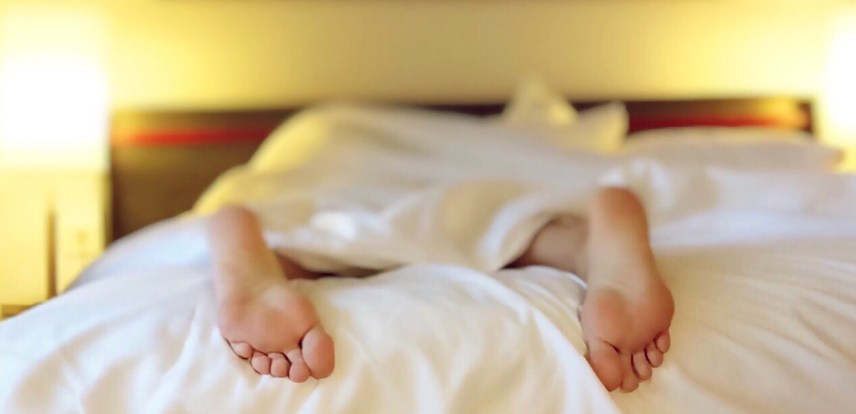 Bare feet sticking out of the covers on a bed