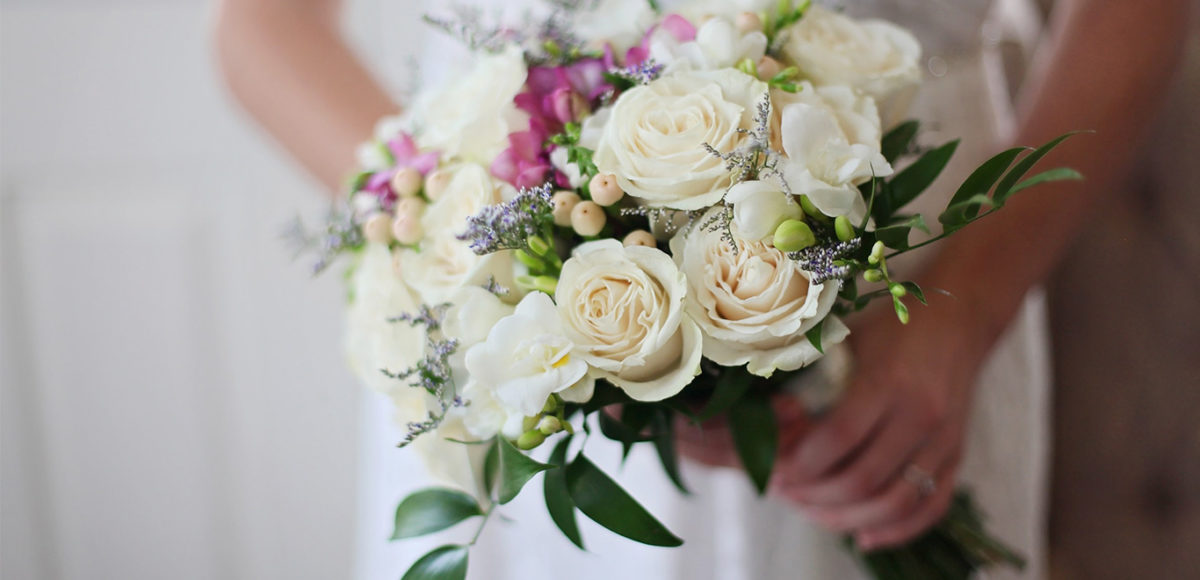 Close up of woman's hands holding wedding bouquet.