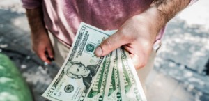 Man's hand holding money, blurred sidewalk