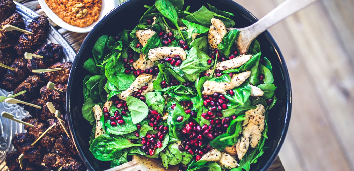 Bowl of spinach, chicken, and pomegranate seeds