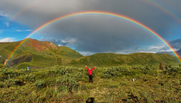 Person standing under a rainbow