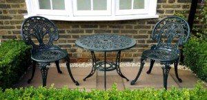 Two metal patio chairs and a metal patio table in an outdoor garden