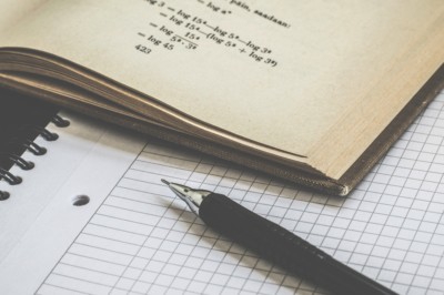 Close-up of math book and pen on top of graph paper notebook