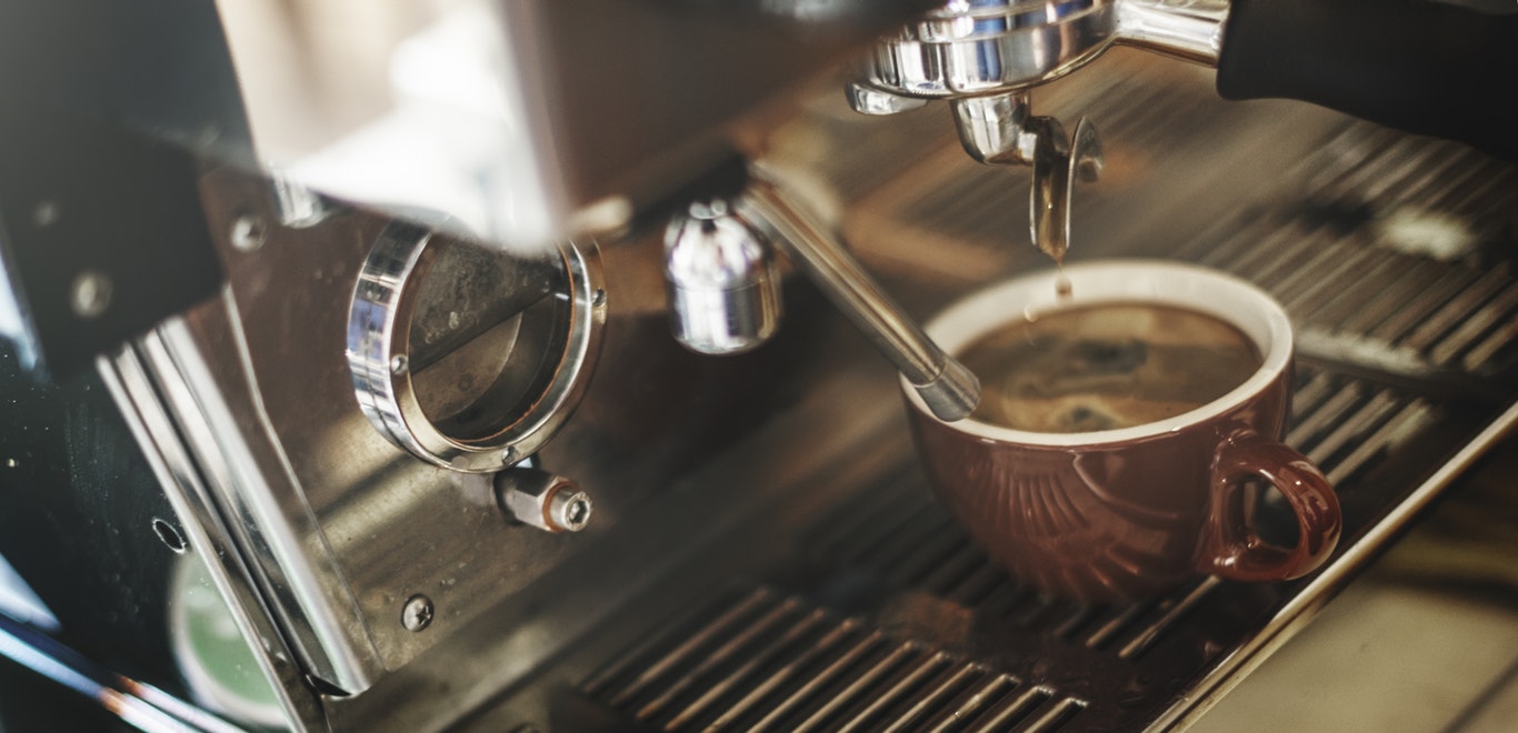Espresso machine dripping coffee into mug, employee office break room ideas for refreshments