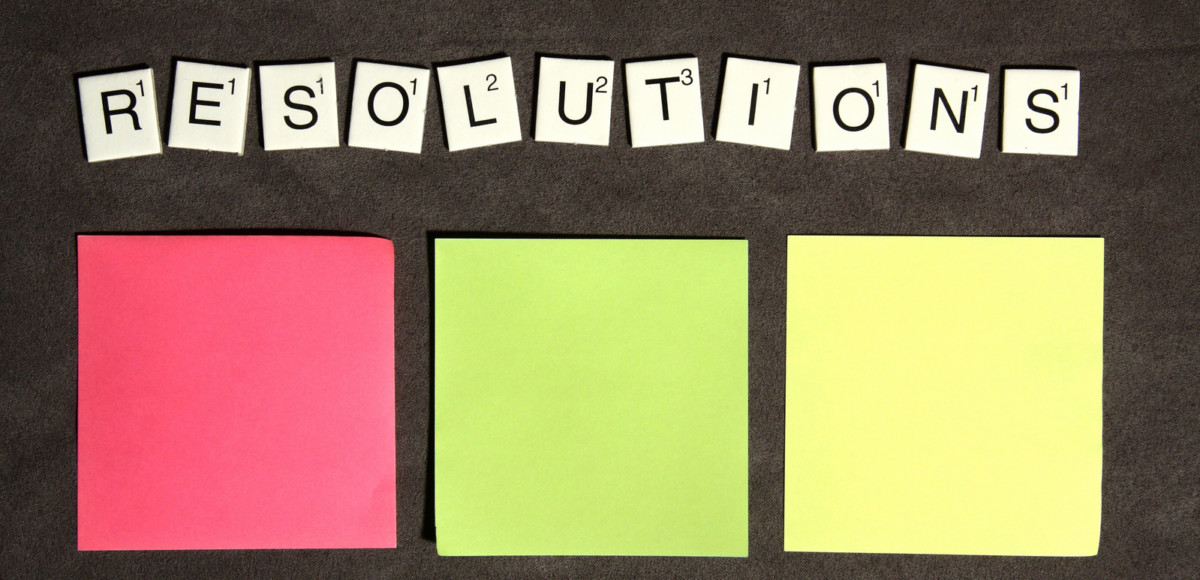 Scrabble tiles with letters spelling "resolutions" and three colorful Post-it notes lined up under them
