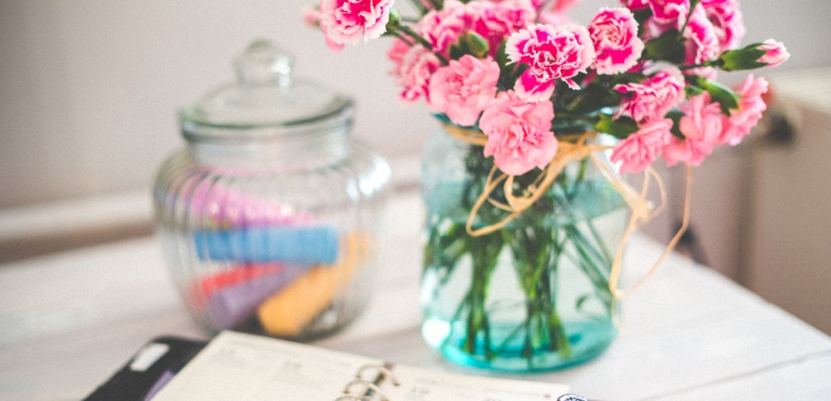 Bright pink flowers in a vase with an open planner on the desk in a startup office