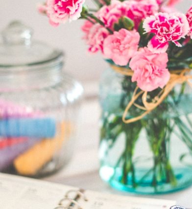 Bright pink flowers in a vase with an open planner on the desk in a startup office