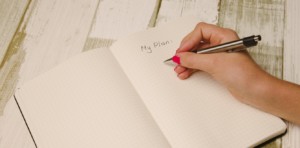 Woman's hand writing in a blank notebook with a heading that says "My Plan."