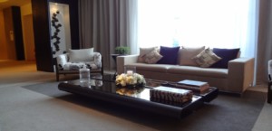 Modern coffee table topped with accessories sitting in front of a beige couch and white chair