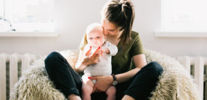 Young mom sitting cross-legged holding her baby