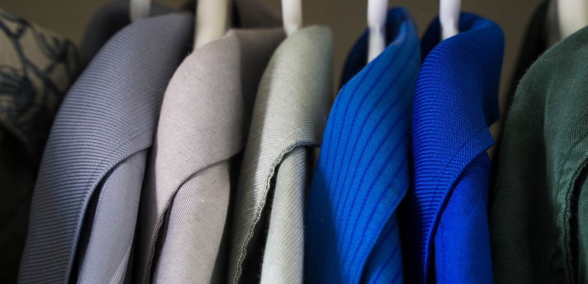 Neat, organized blue and gray blazers on hangers in a closet
