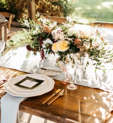 Wooden dining table with flowers and place settings