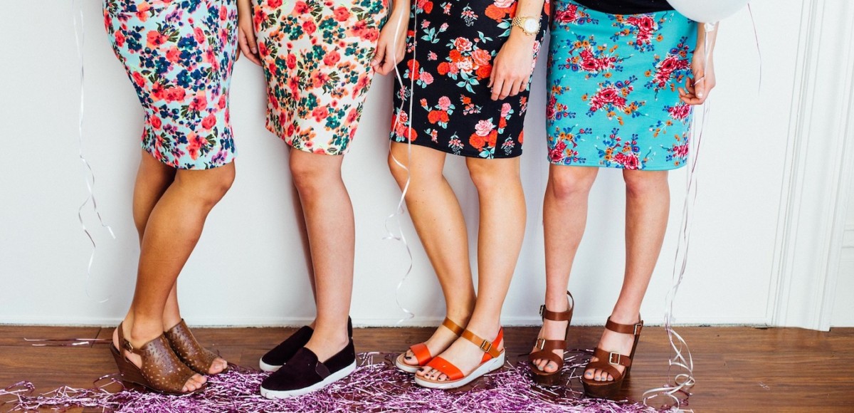 Four women standing together in floral skirts and cute shoes surrounded by festive décor.