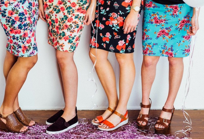 Four women standing together in floral skirts and cute shoes surrounded by festive décor.