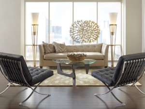 Cream couch, glass coffee table, black chairs, tall light fixtures and spiked chandelier