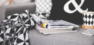 Gray chair with black and white pillows, coffee mug, and magazines
