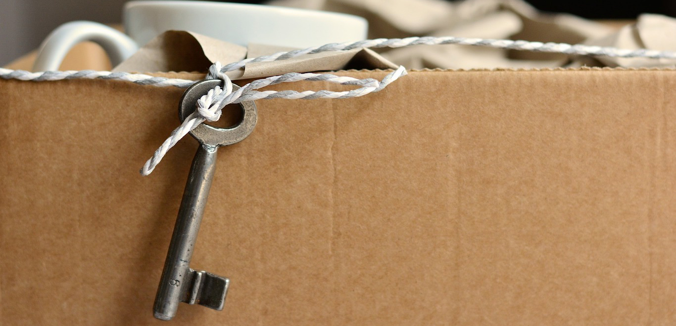 Close up of brown moving box with metal key attached on a string