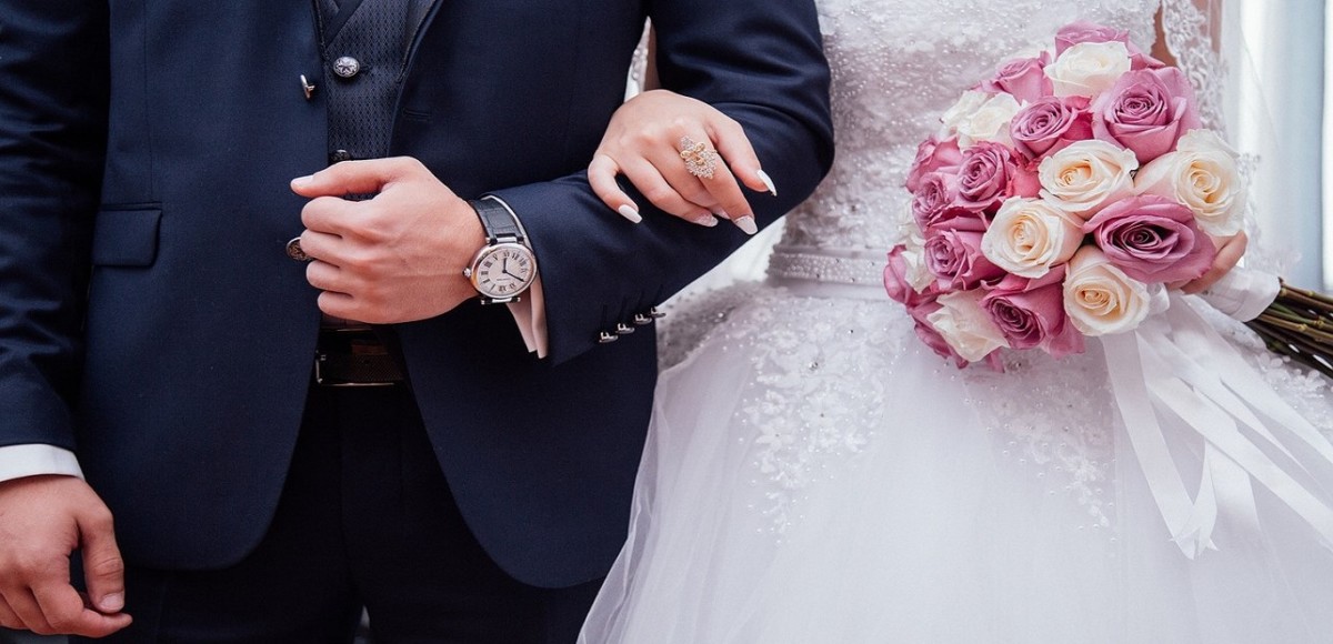 Close-up of bride and groom linked arm in arm
