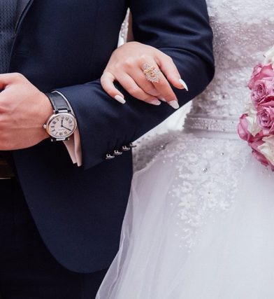 Close-up of bride and groom linked arm in arm