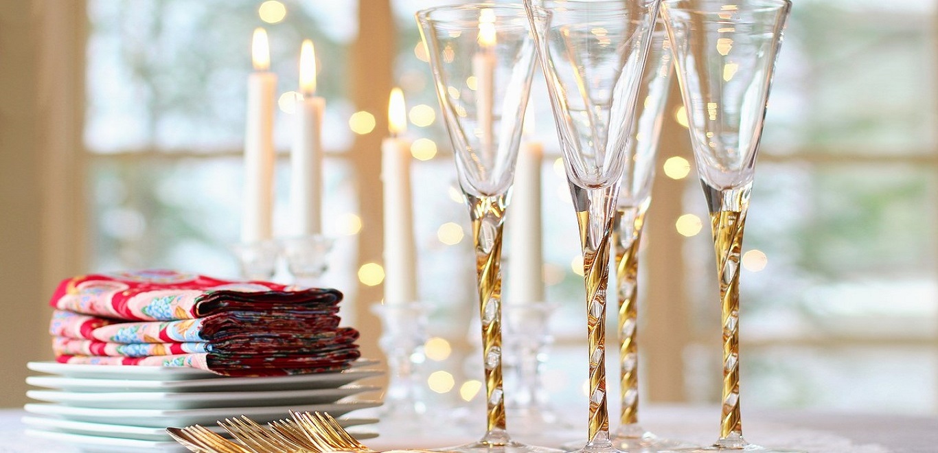 Table with gold flatware, gold-trimmed wine glasses, and tapered candles