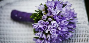 Wedding bouquet with lavender colored flowers wrapped in purple ribbon