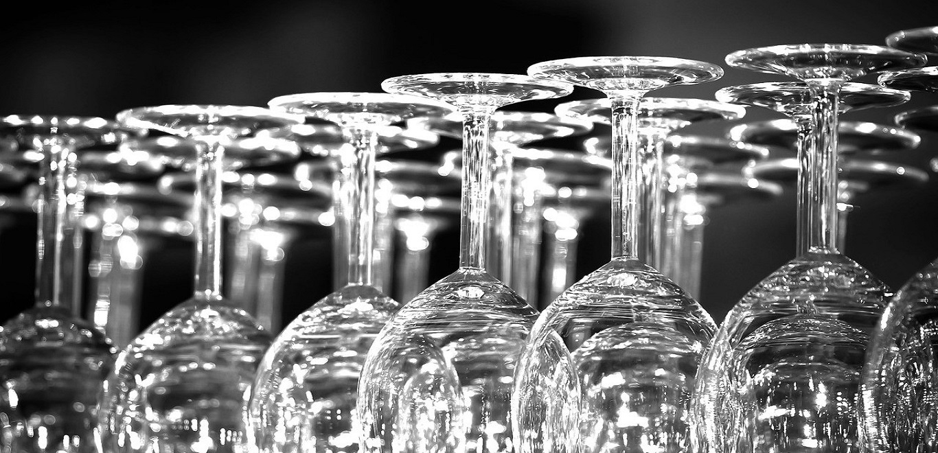A grouping of clear, fragile wine glasses against a black  background
