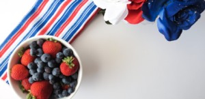 Bowl of strawberries and blueberries with striped napkin and red, white, and blue flowers