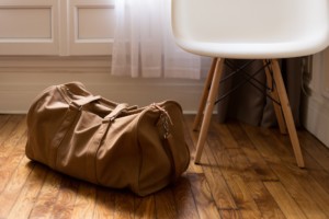 A brown duffle bag packed and ready to go, sitting on a wood floor