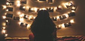 Young woman looking at lighted photos on her bedroom wall