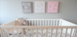 Nursery with a white crib, gray chevron bedding, stuffed animals, and wall art