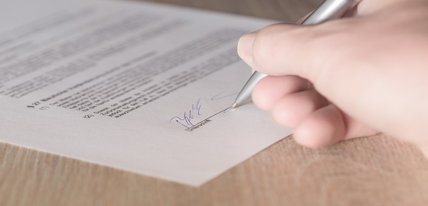 Close-up of renter signing a lease contract in blue ink