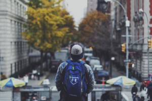 Young man with backpack walking around new city after moving