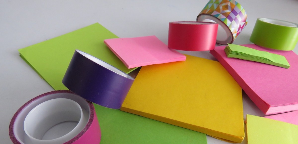 Colorful rolls of washi tape and neon sticky notes in various sizes and shapes
