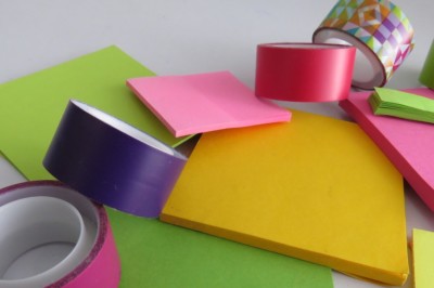 Colorful rolls of washi tape and neon sticky notes in various sizes and shapes