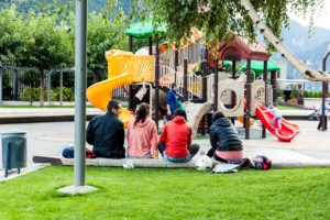 Parents sit and watch children playing on a playground