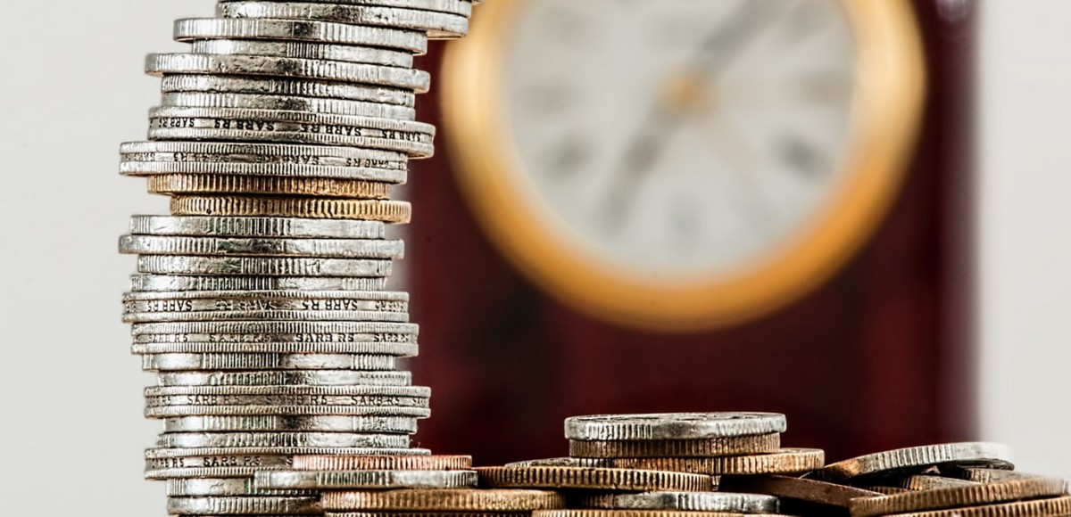 Stack of coins with a blurred clock