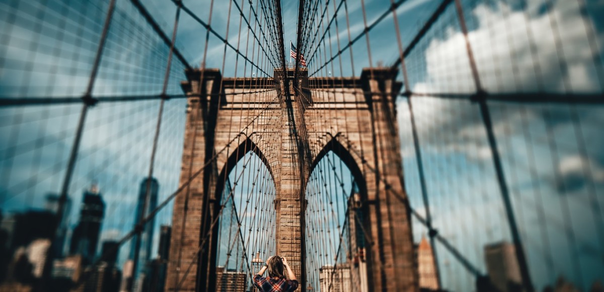 Person taking a photo of a bridge with a blue sky background