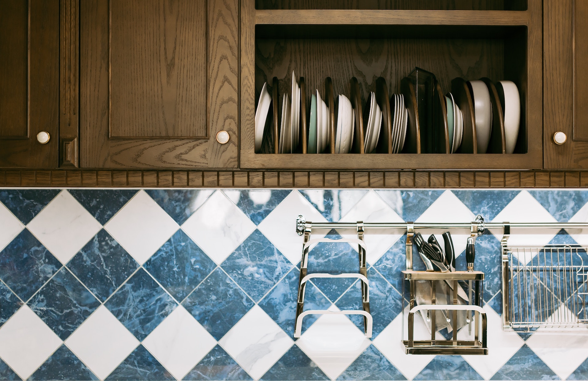 Open shelving in a kitchen that shows off vertical stacks of dishes and silverware above a decorative tile backsplash