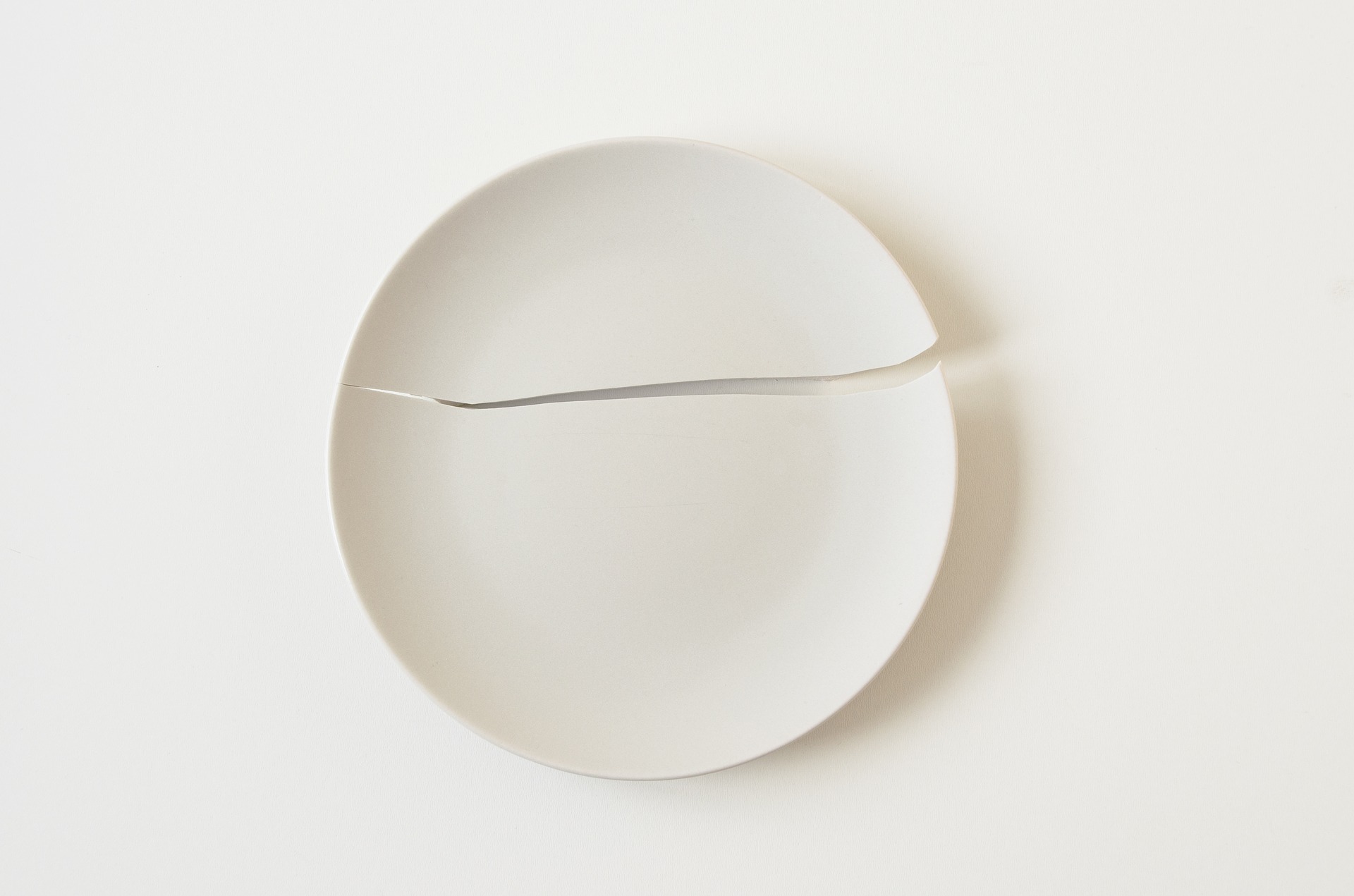  Broken white ceramic kitchen plate on white table