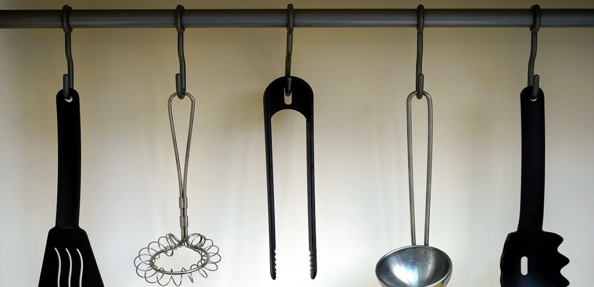 Kitchen utensils hanging from a mounted bar