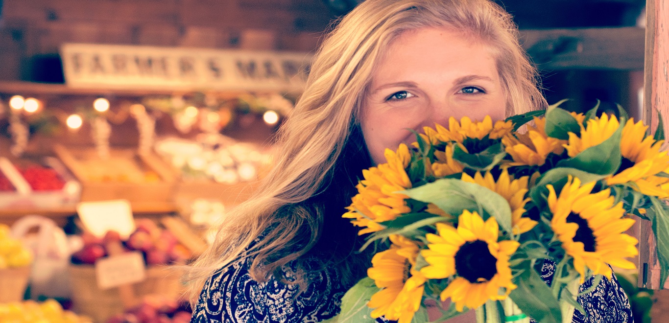 A young woman with flowers at a farmers' market