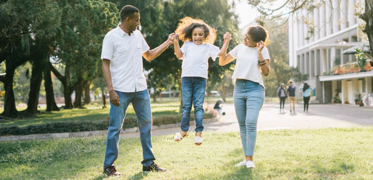 Parents in jeans and white shirts playing with young child