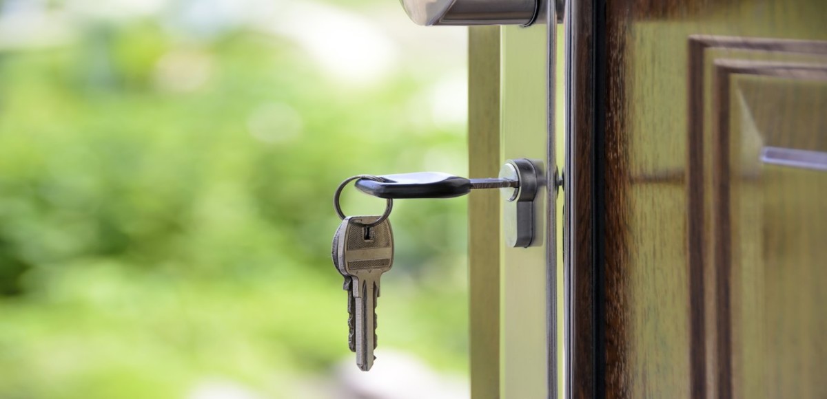 A set of keys hangs in the door of a house