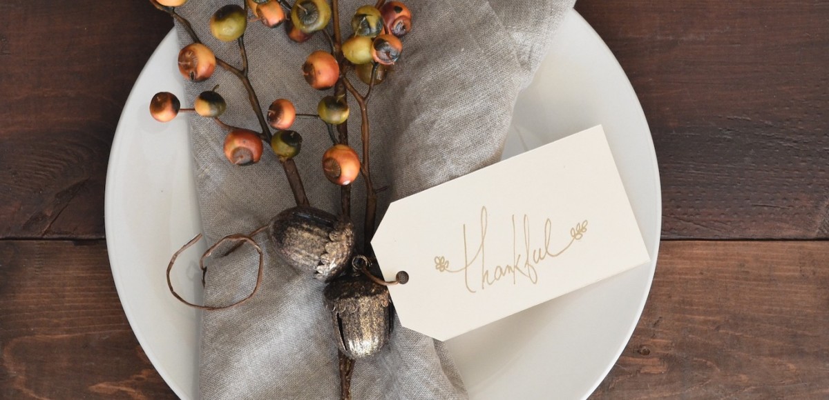 Thanksgiving dinner setting with linen napkin, acorns, and rustic sprig of autumn fruit