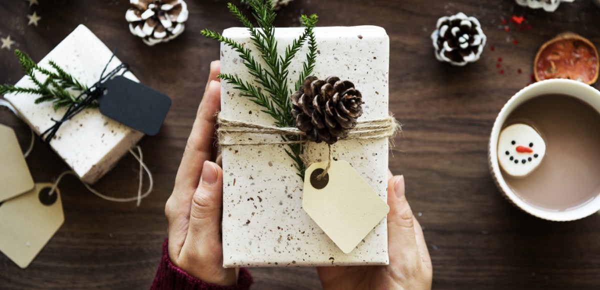 Hands holding present with pinecone and gift tag