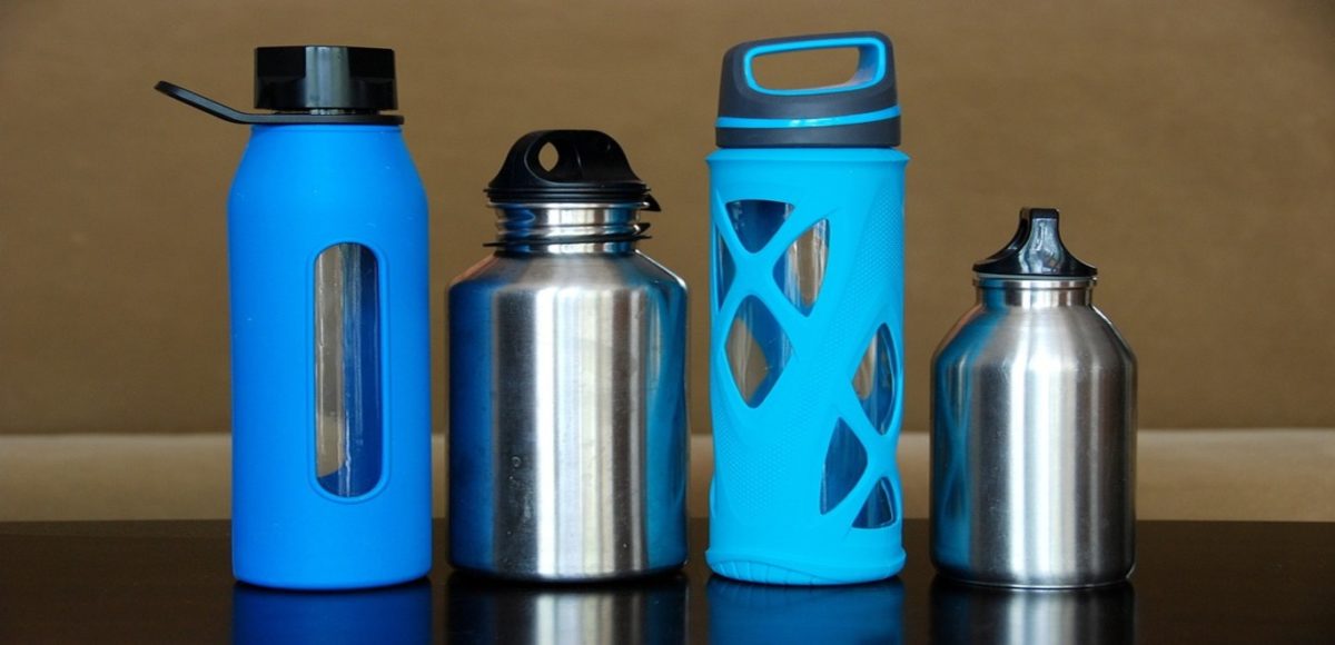 Four reusable water bottles lined up next to each other on a table.