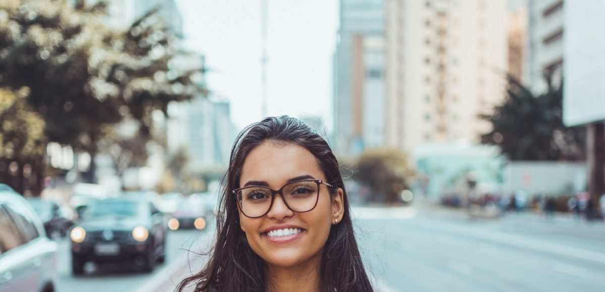 Young woman happy living in her downtown apartment, blurred urban background