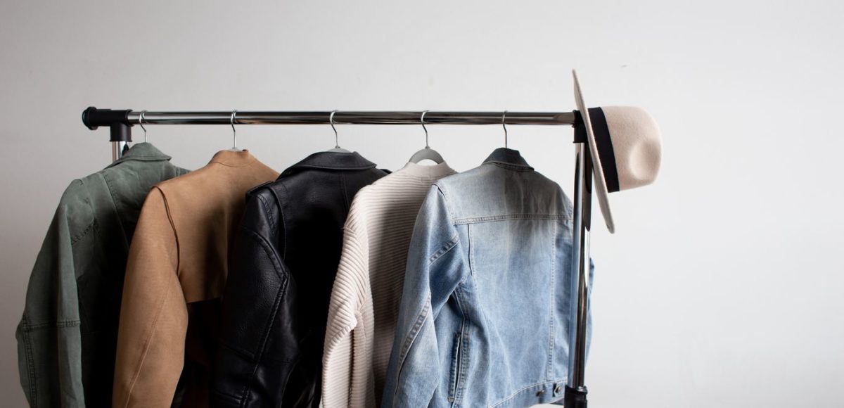 Five women's jackets and a hat hang on a minimalist clothing rack
