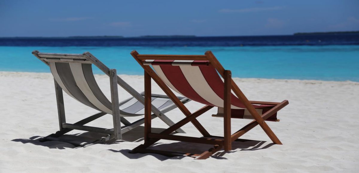 Two empty beach chairs side by side on a sandy beach