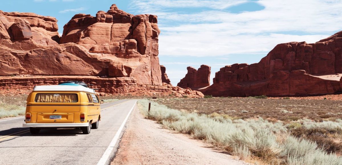 A yellow van travels along a road into the entrance of Arches National Park